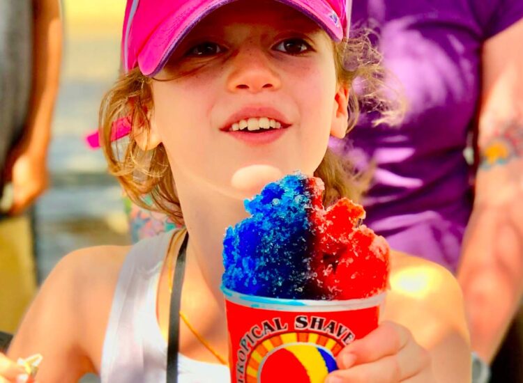 Man and woman posing next to a shaved ice stand