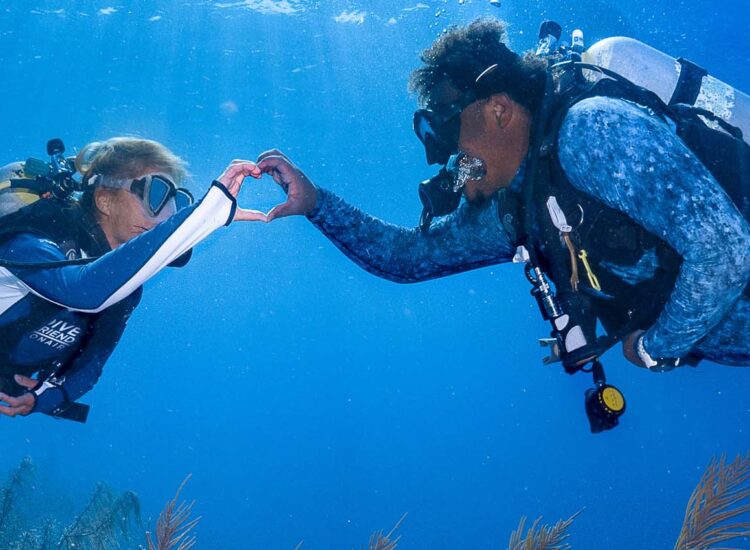 Two divers making a heart with their hands underwater in bonaire