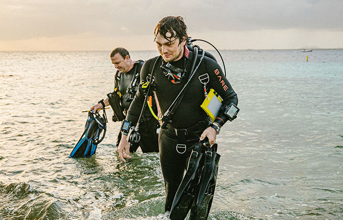 Two men coming out of the water in scuba gear