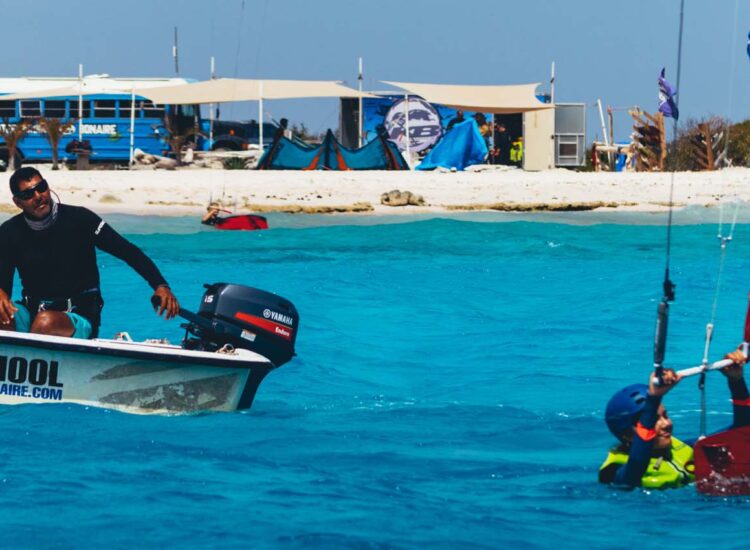 Man on a boat next to a man engaging in a water sport