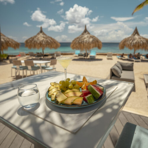 Sunset view at a beach restaurant in Bonaire with palm trees and ocean in the background.