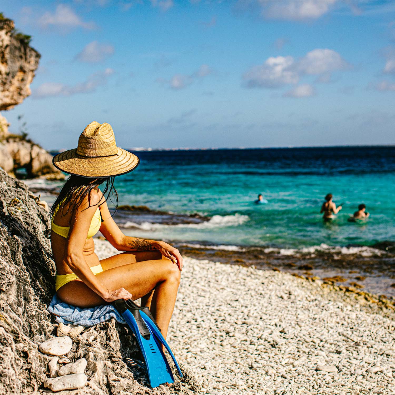 Woman sitting on rock looking at ocean
