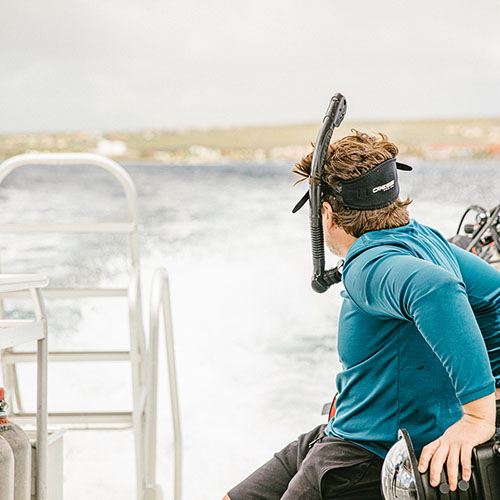 Scuba diver emerging from turquoise waters near Bonaire’s coral reefs.