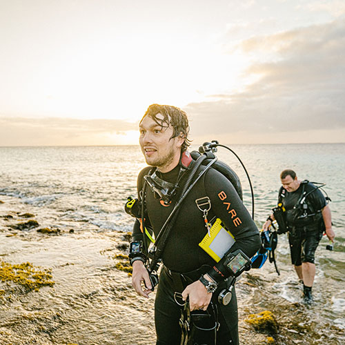 Two men coming out of the water in technical diving equipment setup in Bonaire
