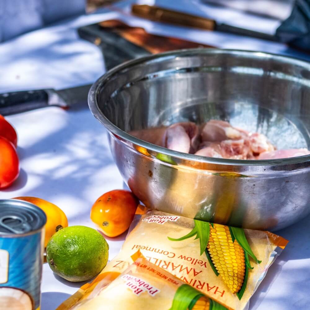 Steel bowl filled with food, with limes and vegetables surrounding it