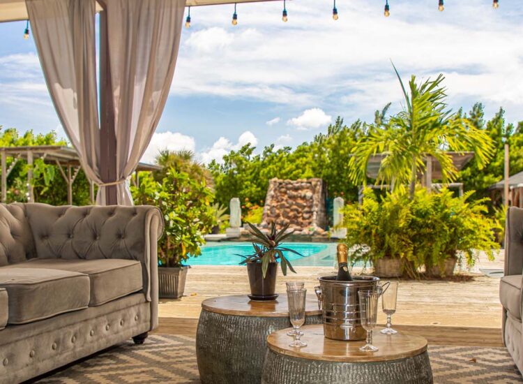 Outdoor lounge area with a couch and armchairs by a pool