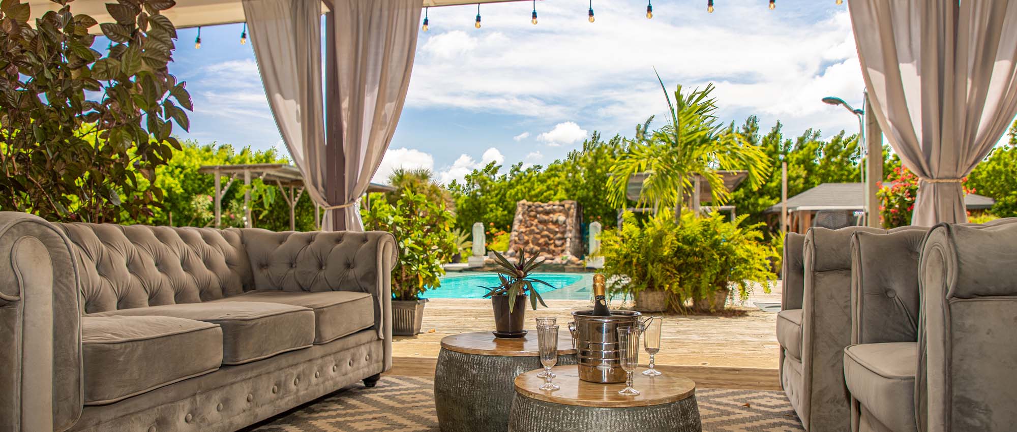 Outdoor lounge area with a couch and armchairs by a pool