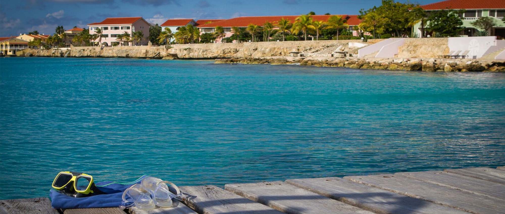 Swimming goggles on a deck above the ocean overlooking a few buildings