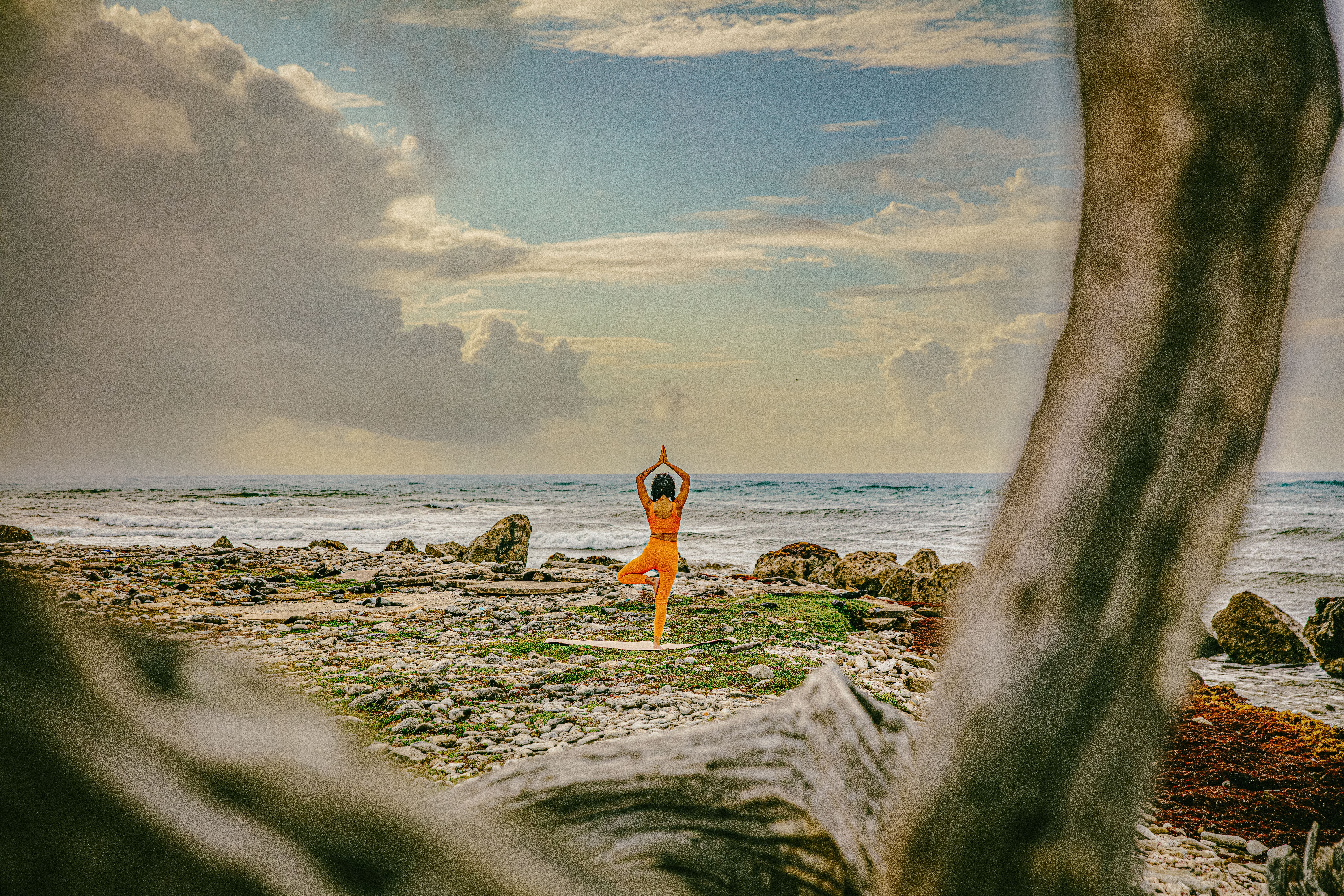 Woman practicing yoga on a serene beach in Bonaire at sunrise.
