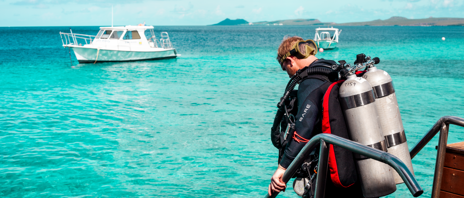 man diving from a boat in bonaire